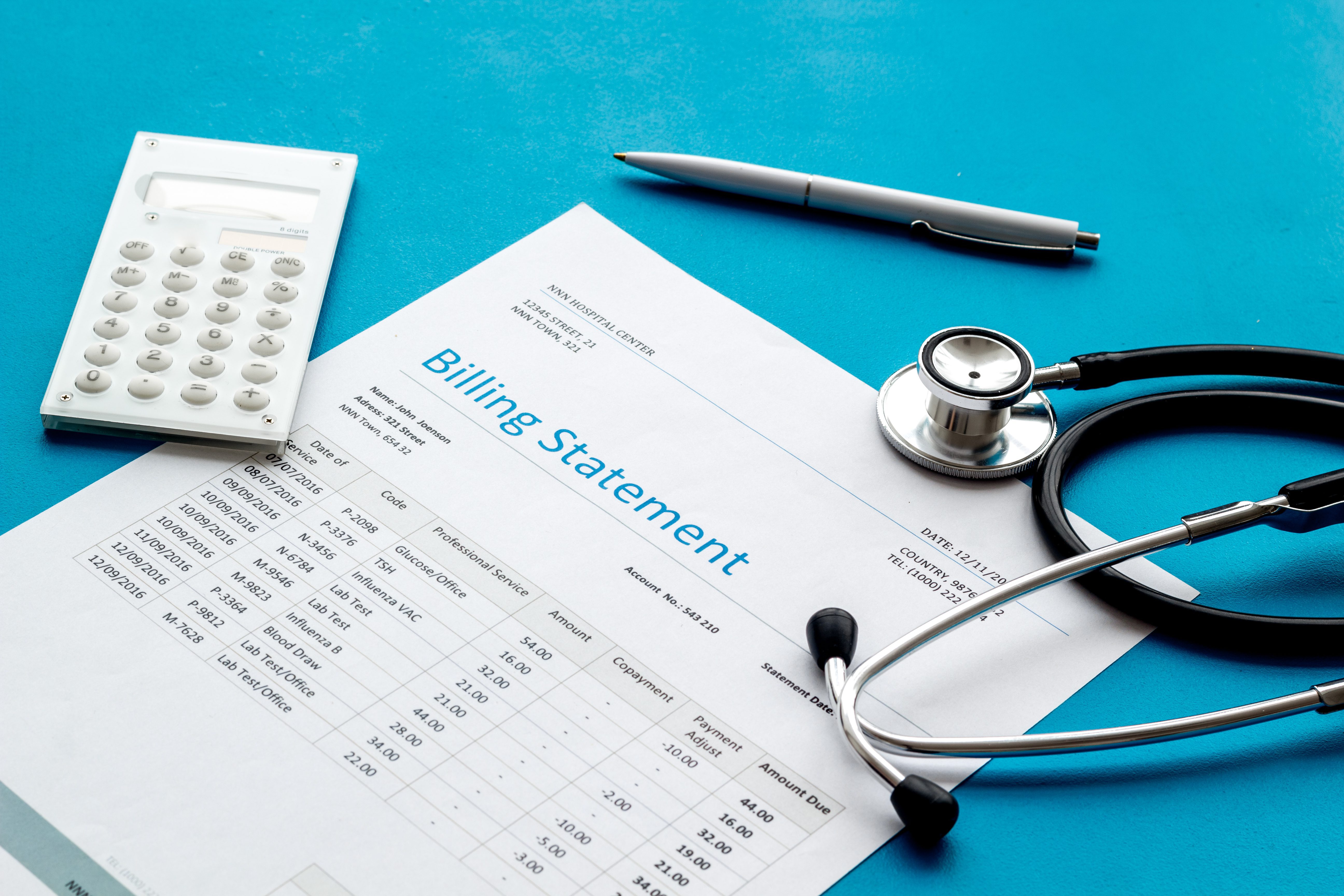 medical treatment bill, calculator and phonendoscope on blue background